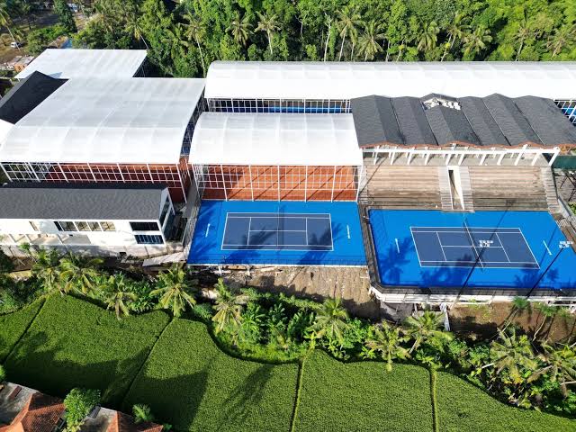 Aerial view of Kula Mani tennis village pickleball courts surrounded by lush green rice paddies in Ubud, Bali